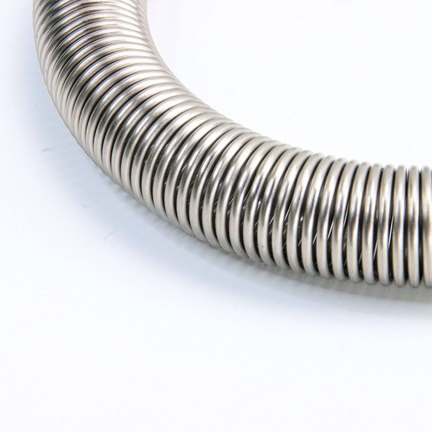 Macro shot of high-tensile steel coil from Pilates Trapeze Spring for Cadillac, highlighting its strength and rust-resistant finish.